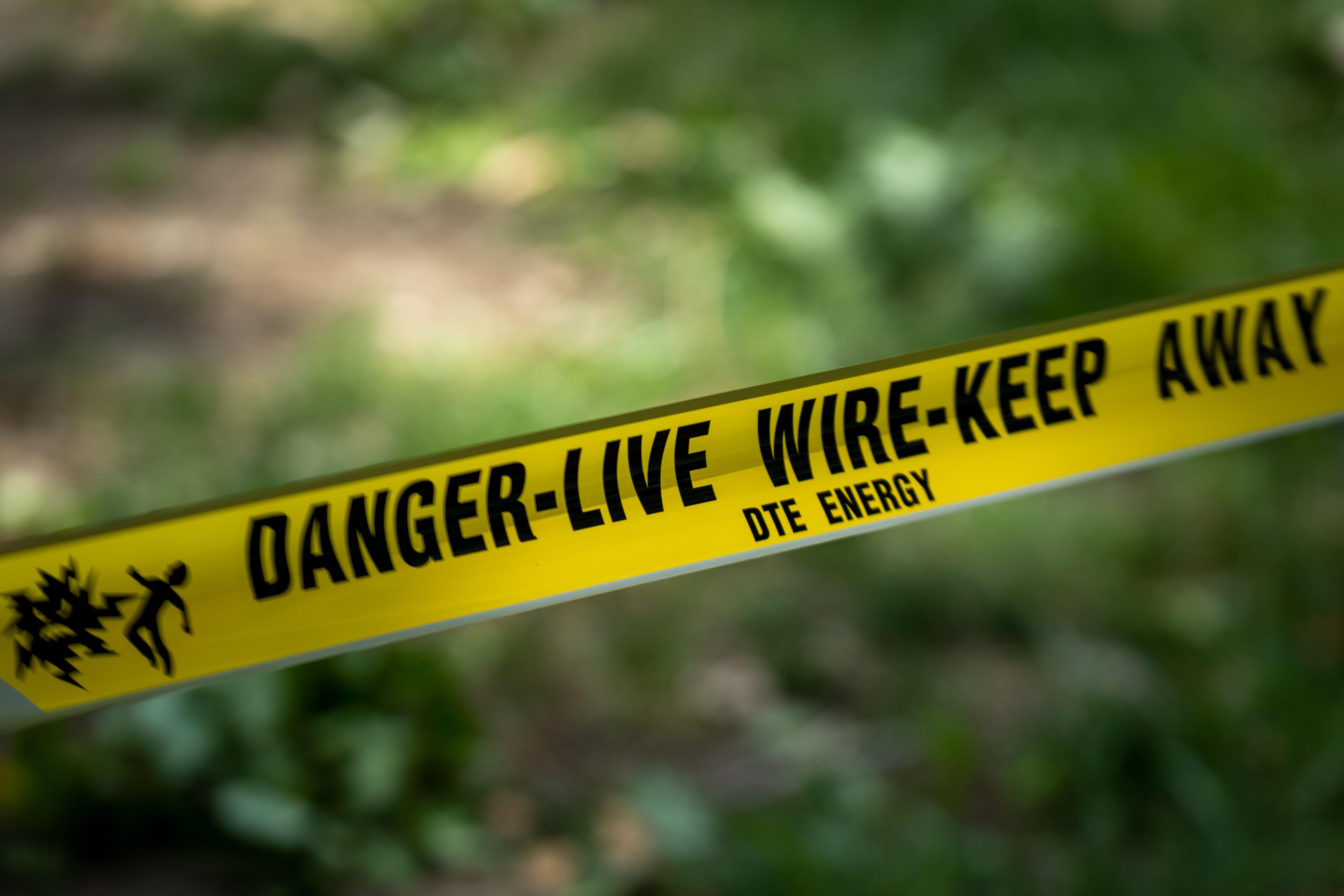 Yellow caution tape that says DANGER-LIVE WIRE-KEEP AWAY and DTE ENERGY written under it