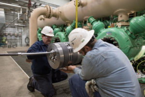 Workers installing a new compressor rod and packing on a natural gas pumping engine in Kalkaska, Michigan