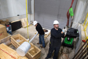 Works remove new compressor rod assemblies from crates to install them as part of a natural gas compressor overhaul project at DTE Energy's facility in Kalkaska, Michigan.