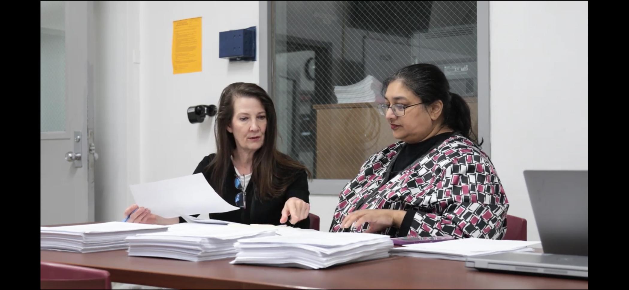 Woman assists female colleague with legal support for returning citizen clinic participant files.