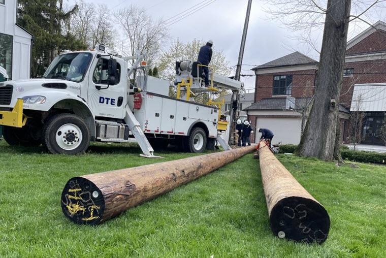 two utility poles lying down toward the camera with a DTE truck in the background