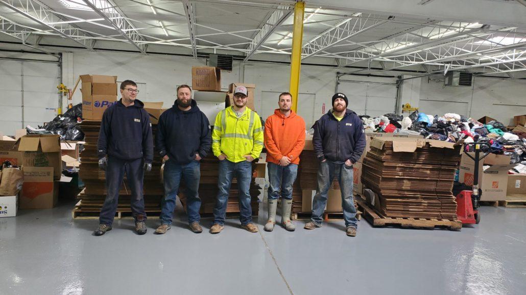 group of five DTE employees standing in a line for a photo in the warehouse
