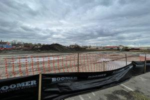 open pavement with orange fencing and black tarp around it