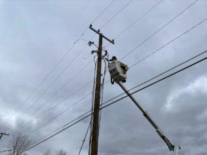 DTE worker in bucket truck lifted and working on a utility pole on gloomy day