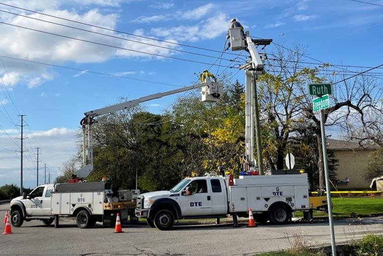 DTE bucket truck with worker up working on a power line on sunny day